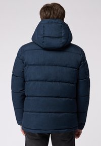 Marineblå pufferjakke med hætte, der har et quiltet design og en struktureret finish. Inkluderer en høj krave og elastiske manchetter.