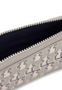 Zippered pouch in a patterned fabric with wavy grey lines on a light background. Interior lined in dark fabric with silver zipper hardware.
