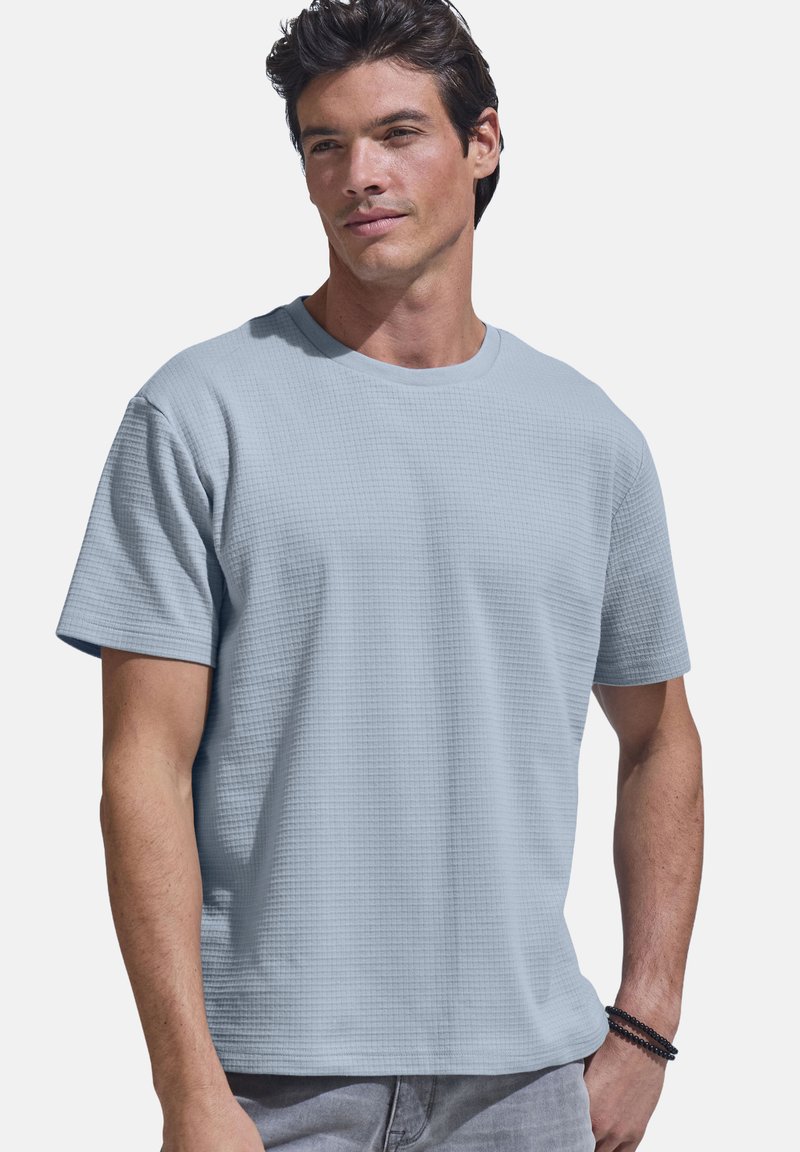 Hellblaues T-Shirt mit kurzen Ärmeln, strukturiertem Muster, rundem Ausschnitt und legerer Passform. Hergestellt aus atmungsaktivem Stoff. Lässiges Design.