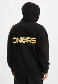 Fekete kapucnis pulóver, amely szövetből készült, hátul nagy arany "DNGRS INVADER" logóval. Lazán illeszkedik és kapucnija is van.