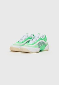 Scarpe sportive con tomaia in rete verde chiaro e bianca, motivo testurizzato, suole bianche spesse e dettagli verdi sui lati e sui lacci.