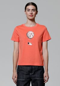 Korallenfarbenes Baumwoll-T-Shirt mit einem grafischen Motiv eines Astronauten, der einen ballonförmigen Mond hält. Kurzarm, Rundhalsausschnitt, entspannter Schnitt.