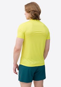 Cămașă sport galbenă, cu mânecă scurtă, având un material texturat și un design ajustat, asortată cu șorturi teal.