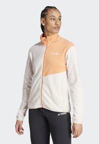Chaqueta de forro polar con cremallera, que presenta un diseño en bloques de color coral y crema. Textura suave, incluye el logo 'TERREX' en el pecho.