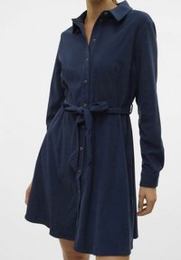 Abito camicia blu navy a maniche lunghe con abbottonatura frontale, vita legata e colletto. Presenta un tessuto testurizzato e una silhouette aderente.