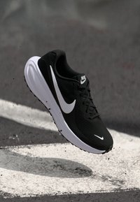 Black athletic shoe with breathable mesh upper, white Swoosh logo, white midsole, and textured outsole, designed for running or training.