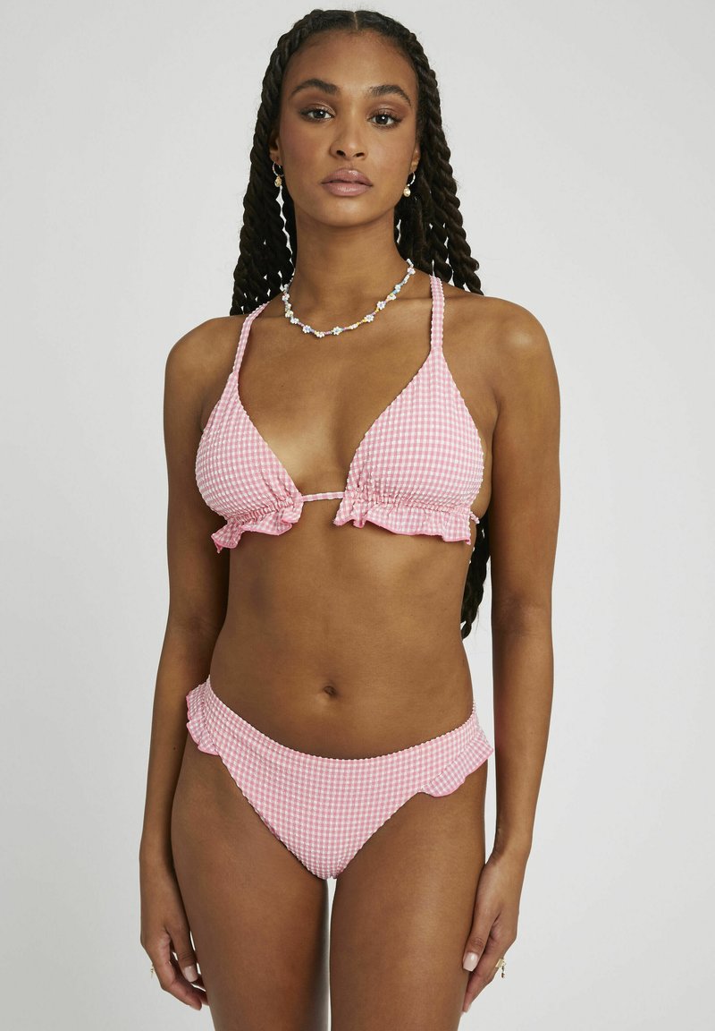 Bikini en vichy rose avec des volants. Haut triangle et bas taille basse avec des bords en forme de vagues. Le matériau semble lisse avec un motif en quadrillage.