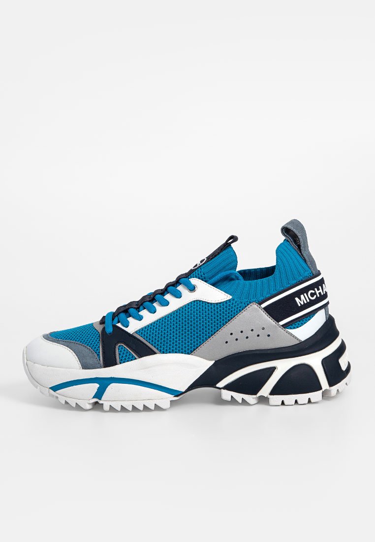 Die Sneakers verfügen über ein Netz-Obermaterial in Blau und Dunkelgrau, eine weiße Zwischensohle und ein robustes Sohlen-Design mit einer strukturierten Oberfläche und kontrastierenden Akzenten.