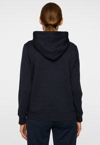 Felpa blu navy con una vestibilità rilassata, grande cappuccio, polsini e orlo a coste, realizzata in tessuto morbido, priva di motivi o loghi visibili.