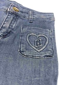 Jean en denim avec une broderie en forme de cœur sur la poche arrière. Lavage bleu clair avec un design classique à cinq poches et fermeture à bouton en métal.