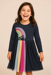 Marineblaues Langarmkleid mit einem Regenbogen-Motiv und einem mehrfarbigen Tüllrock mit rosa, gelben und blauen Streifen.