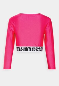 Rosa, glansig långärmad croptop med en midja prydd med svart och vitt logotyp. Slät textur och åtsittande design. Bakvy visas.