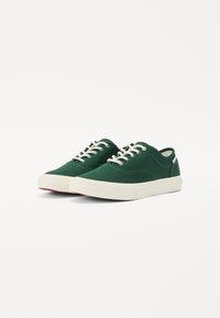 Grüne Leinen-Sneaker mit weißen Schnürsenkeln, runder Zehenpartie, strukturiertem Obermaterial und Gummisohle. Einfaches, klassisches Design mit minimalen Akzenten.