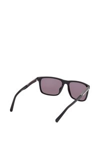 Mustat aurinkolasit mattapinnalla, violetit linssit ja hopeiset yksityiskohdat sangoissa. Kevyt muotoilu suorin sangoilla.