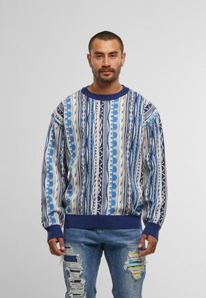 Blue patterned sweater with a crew neck, featuring vertical stripes in varying shades of blue and cream, ribbed navy cuffs and hem.