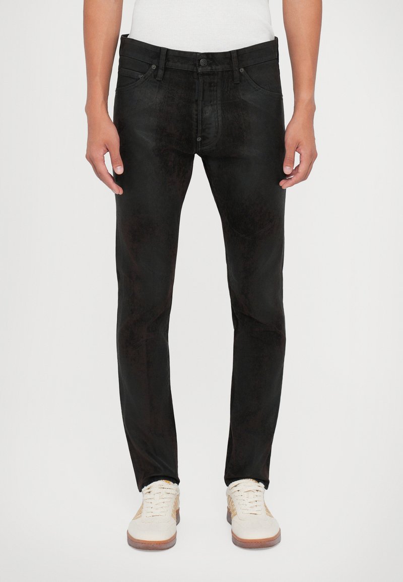 Jeans in denim nero con vestibilità slim, caratterizzati da una sottile texture spazzolata. Tasche anteriori e chiusura con bottone, abbinati a sneakers bianche.