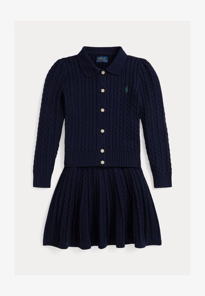 Vestido de malha azul marinho com gola canelada, fecho debotões na frente e saia plissada. Apresenta um design de tricot com cabos e um pequeno logótipo no peito.