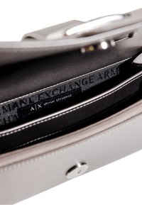 Borsa sintetica grigia dallo design elegante, con chiusura a scatto in argento, etichetta di branding interna e fodera nera a contrasto.