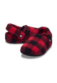 Rode en zwarte geruite slippers van zacht, pluizig materiaal met een ronde neus, open achterkant en een knoopdetail aan de zijkant.