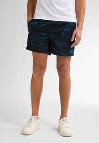 Czarne szorty kąpielowe w niebieski kwiatowy wzór, elastyczny pas, boczne kieszenie i niewielki detal z logo na dolnym brzegu. W połączeniu z białymi sneakersami.