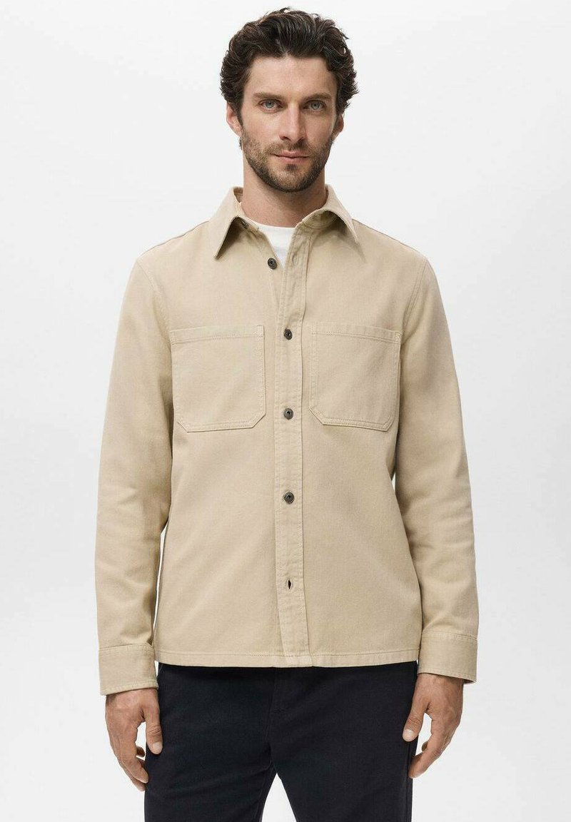 Beige bomulds skjortejakke med lange ærmer, frontlommer, knaplukning og en struktureret krave. Glat texture og afslappet pasform.