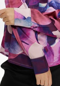 Langärmliges Hemd mit buntem Blumenmuster in den Farbtönen Pink, Lila und Blau. Weicher Stoff mit strukturierter Oberfläche und kontrastierenden Bündchen.