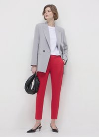 Grau doppelt-knöpfiges Blazer, weißes Rundhals-T-Shirt, rote figurbetonte Hose, schwarze Handtasche und schwarze spitze Absatzschuhe.
