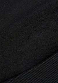 Czarna tkanina o dwóch fakturach: gładki, prążkowany dzianinowy materiał kontrastujący z miękką, pluszową, puszystą powierzchnią w ciemniejszym odcieniu czerni.