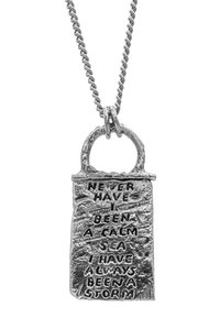 Silverpendel på en kedja, med en graverad rektangulär design och en texturerad yta med orden, "Aldrig har jag varit ett lugnt hav..."