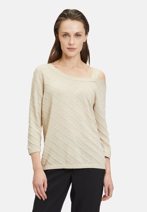 Maglione beige off-shoulder con maniche a 3/4, presenta strisce testurizzate diagonali e un ampio scollo. Realizzato in un tessuto leggero e scintillante.