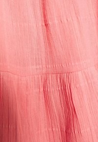 Heller pinker Stoff mit einer strukturierten, zerknitterten Oberfläche. Verfügt über horizontale Nähte und sanfte Raffungen. Weiches und leichtes Material.