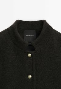 Dark brown wool coat featuring a stand collar, gold buttons, and a subtle textured finish. Label reads "Massimo Dutti."