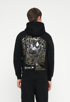 Black hoodie featuring a graphic print on the back with a character in white and gold outline against a spider web design.