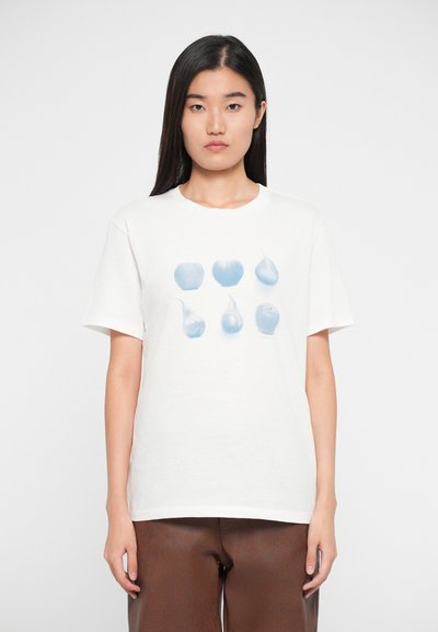 T-shirt bianco in cotone con una grafica azzurro chiaro di mele e pere disposte in due file, maniche corte e scollatura a girocollo.