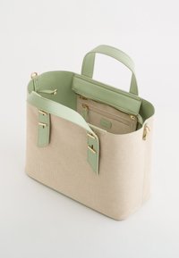 Beige canvas handtas met lichtgroene synthetische leren accenten, bovenhandvatten en een binnenzak met rits. Voorzien van details in goudkleurige hardware.