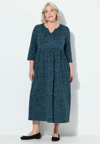 Robe longue teal avec un motif léopard, dotée d'un décolleté en V et de manches ¾. Le tissu semble doux avec un design ample et fluide.