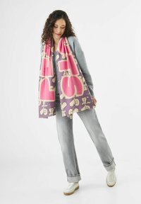 Paarse sjaal met grote roze tekst en een cartoonachtige uitstraling. Gemaakt van zachte stof, met franje randen en een gemiddelde dikte.