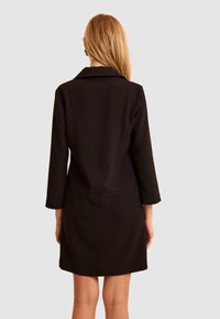 Czarny strukturalny płaszcz z kołnierzem, rękawami do połowy przedramienia oraz detalem szwu w talii, o gładkiej fakturze i długości do kolan.