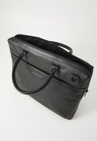 Sac à ordinateur portable en cuir noir avec deux poignées supérieures, surface texturée, fermeture éclaire et un patch logo. Dispose d'un intérieur spacieux pour le rangement de l'ordinateur portable.