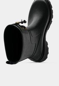 Μαύρη λαστιχένια μπότα με στρογγυλεμένη μύτη, υφή και πάτο με έντονο πέλμα. Διαθέτει κορδόνια και θηλιά στο πίσω μέρος.