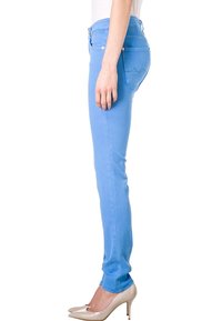 Jeans ajustados de denim en color azul, con un diseño de cinco bolsillos y detalles de costura sutiles. Combinados con zapatos de tacón nude.