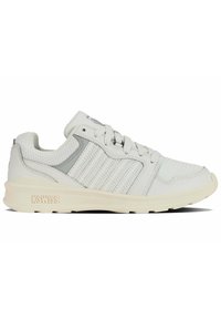 Baskets de sport blanches avec une tige en mesh et en cuir, présentant des accents gris et trois rayures texturées. Semelle en caoutchouc épaisse avec un logo.