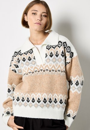 Maglione lavorato a maglia in crema, beige e grigio chiaro con motivi geometrici neri. Presenta un colletto morbido e ampio e un orlo a coste.