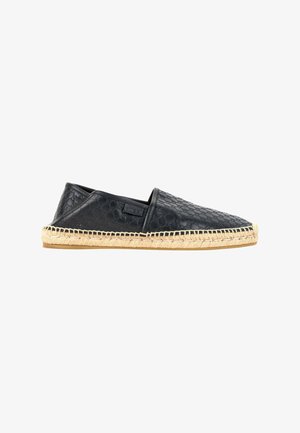 Chaussure espadrille en cuir noir avec semelle en jute tissée cousue, motif embossé sur la tige et design slip-on vue de profil.