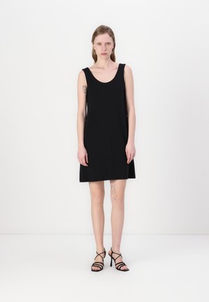 Black sleeveless dress with a scoop neckline, fitted bodice, and flared hem. Worn with strappy black high-heeled sandals. Smooth texture.