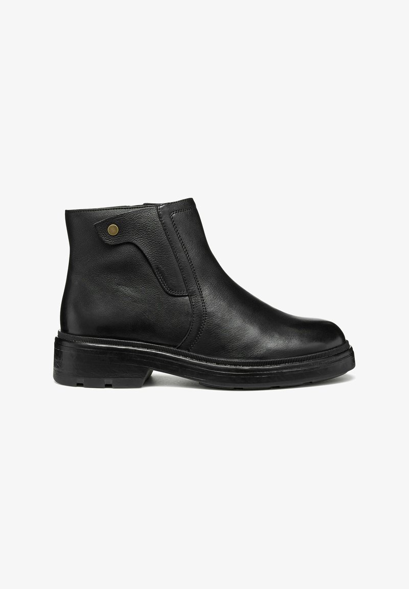 Bota de tobillo de cuero negro con textura suave, panel elástico lateral y puntera redonda. Presenta un tacón bajo y un sutil acento dorado cerca del tobillo.
