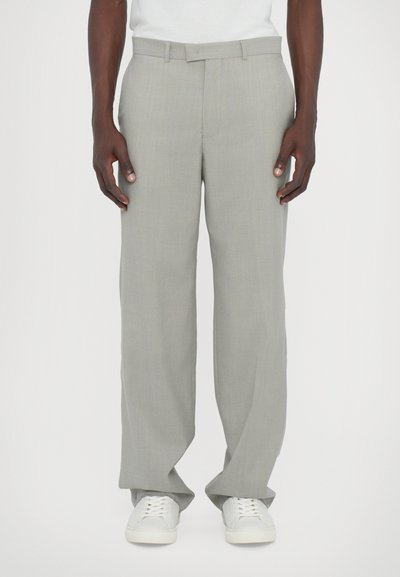 Ανοιχτό γκρι παντελόνι φάρους από υφή υφάσματος, με ίσιο μπροστινό μέρος και πλαϊνές τσέπες, συνδυασμένο με λευκά αθλητικά παπούτσια.