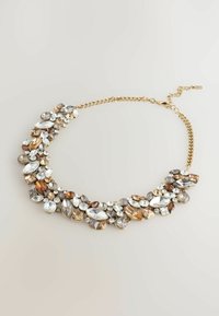 Collana dichiarativa con catena in tonalità oro e un bouquet di cristalli sfaccettati di diverse forme in tonalità argentate e calde, che riflettono la luce.