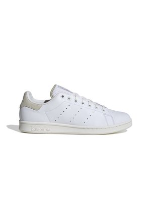 Białe buty sportowe Adidas Stan Smith z perforowanymi paskami i jasnoszarnym zapiętkiem na białym tle.