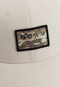 Bežna бейзболска kapa с текстурирана површина, с камуфлажен етикет на патч со црна рамка и отпечатени детали.